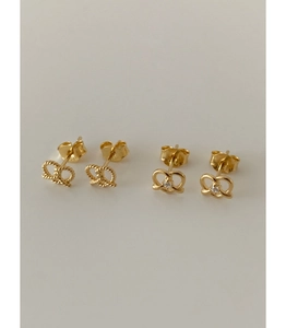 Close-up of twisted gold pretzel earrings with polished finish and cubic zirconia inlay