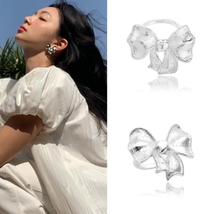 Detailed view of silver bow ring and earrings with heart center and brushed metal texture