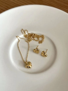 Macro de l'ensemble collier et boucles d'oreilles cœur en argent 925 doré dans un bol