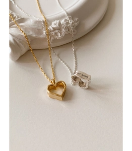Detail of hollow heart pendants in gold and silver with Love ya engraving on the side