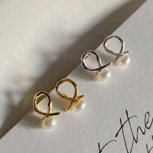 Macro detail of 925 silver cross knot stud earrings with white freshwater pearls