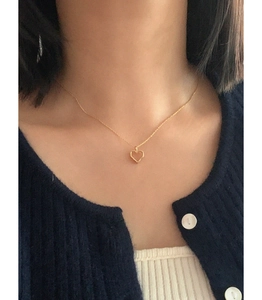 925 sterling silver hollow heart necklace in gold worn by a model on a blue knit sweater