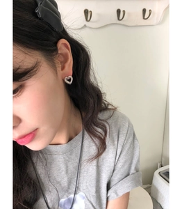 Close-up of minimalist hollow heart silver earrings worn by a model in a natural setting