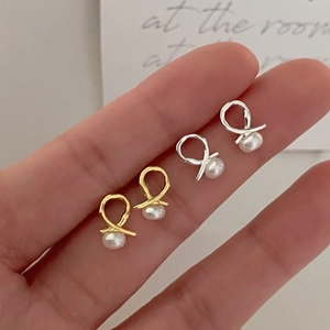 Detailed close-up of small 925 silver pearl stud earrings in gold and silver finishes