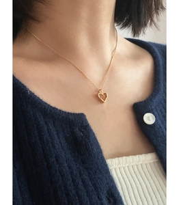 Close-up of a minimalist gold hollow heart necklace worn on a female collarbone