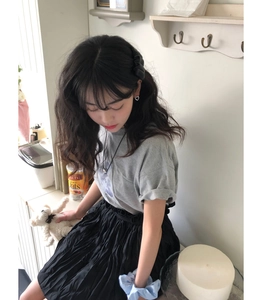 Detail shot of hollow heart studs paired with a pleated skirt and casual grey cotton t-shirt