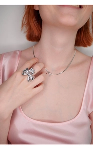 Close-up of elegant silver bow ring and matching necklace set on a model