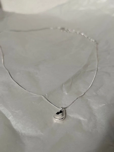 Close-up of a minimalist S925 sterling silver teardrop pendant on a delicate cable chain