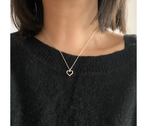 Detail of minimalist 925 silver hollow heart necklace worn on a black sweater background