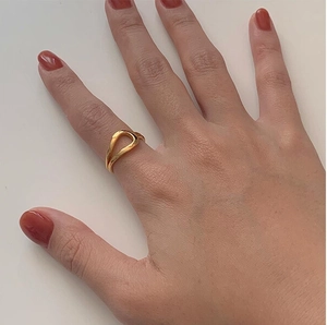 Close-up of a minimalist gold knotted open ring on a model with red nails