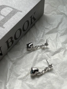 Macro shot of 925 silver heart earrings with arrow charms on crinkled paper