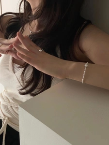 Close-up of minimalist 925 sterling silver ball chain bracelet and ring on a model