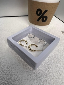 Detailed view of gold and silver S925 sterling silver twisted hoop earrings in a display box
