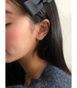 Close-up of a 925 sterling silver pretzel shaped stud earring on a female earlobe