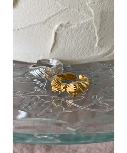 Textured bow-knot adjustable rings in gold and silver finish on a glass tray
