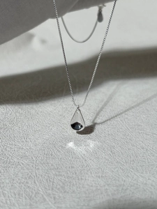 Macro view of a mirror-polished teardrop pendant on a silver S925 box chain necklace
