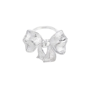 Silver bow knot ring with brushed texture and tiny heart detail on white background
