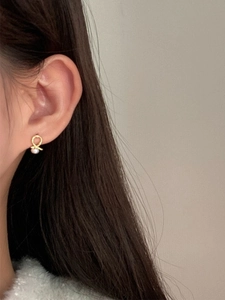 Crossed 925 sterling silver studs with round natural pearls on female model's ear