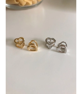 Macro detail of 3D hollow heart earrings set in polished gold and silver plated finish