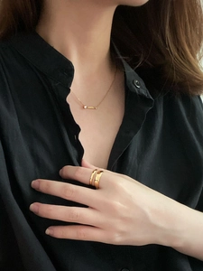 Ensemble collier en perles dorées et bague double couche porté sur un modèle féminin