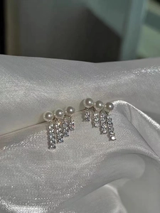 Detail of S925 silver earrings with pearls and zircon tassels on silk fabric