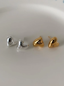 Macro detail of irregular heart studs with sparkling zircons in gold and silver finishes