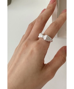 Close-up of a 925 sterling silver bow ring with silk texture worn on a finger