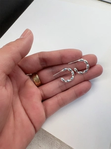 Macro detail of S925 sterling silver beaded C-shaped hoop earrings with a modern design