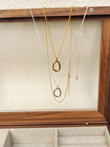 Detail of irregular oval hollow pendants in gold and silver on a wooden jewelry display