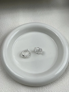 Macro view of multi-layered silver S925 sterling silver hoop earrings on ceramic tray