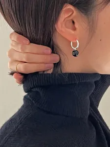 Boucles d'oreilles créoles S925 argent avec onyx noir portées par un mannequin en col roulé