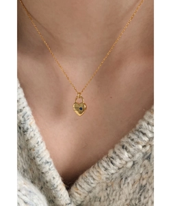 Collier médaillon cœur doré avec pierre bleue porté sur un pull en maille gris