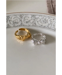 Close-up of gold and silver S925 sterling silver bow rings with textured striped details