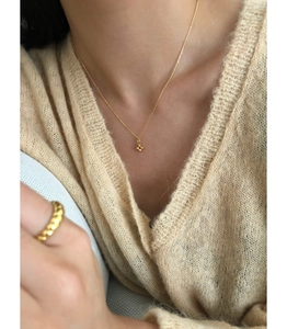 Gros plan du collier croix en argent 925 et de la bague tressée en or sur un mannequin