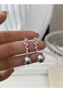 Macro detail of elegant silver drop earrings with sparkling crystals and grey pearls