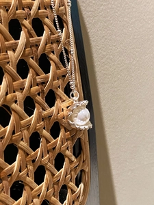 Close-up of S925 silver shell pendant necklace with a white pearl on a woven texture