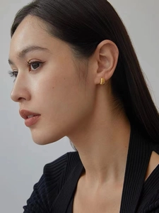 Close-up of golden croissant earrings with textured horizontal stripes on a model