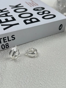 Detail of silver S925 multi-layered hollow hoop earrings with textured finish