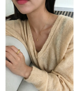 Gros plan d'un collier croix en argent 925 et d'une bague texturée portés par un mannequin