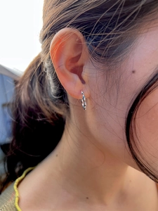 Close-up of minimalist sterling silver twisted hoop earring on a female model