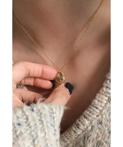 Gros plan du collier médaillon cœur doré avec pierre bleue sur un pull en maille
