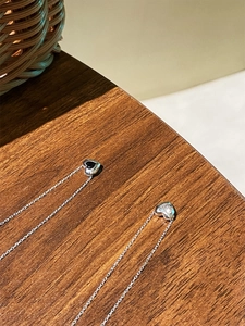 Gros plan de colliers minimalistes en argent S925 avec pendentifs en cœur noir et blanc