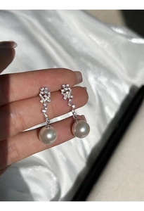Detailed macro of S925 silver pearl drop earrings with sparkling zircon floral studs