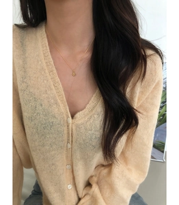 Gros plan du collier croix doré porté par un mannequin sur un pull en maille