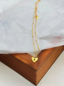 Détail d'un pendentif cœur en argent 925 sur une chaîne à billes délicate dorée