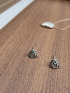 Detailed macro view of vintage 925 sterling silver flower stud earrings on wood