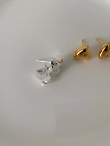 Detailed view of silver and gold heart stud earrings with sparkling starburst zircon center