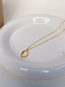 Close-up of a minimalist 925 silver gold-plated necklace with oval hollow pendant