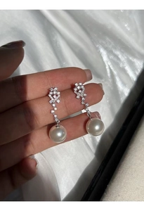 Macro detail of elegant S925 silver drop earrings with zircons and large white pearls