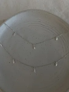 Vue détaillée des colliers en argent S925 avec pendentifs feuilles sur un plat en céramique